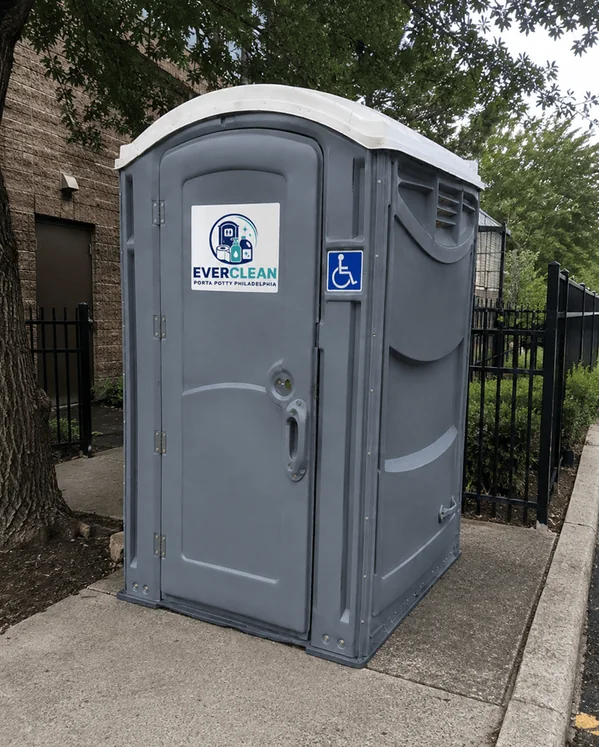 ADA accessible porta potty with wheelchair symbol beside a sidewalk